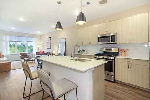 A kitchen with a white counter top and wooden floors.